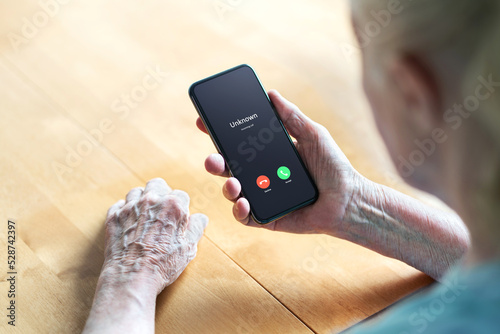 Phone call to old woman from scam or fraud caller. Elder senior answering to unknown number. Smartphone scammer or mobile hoax, catfish or phishing concept. Stalker or stranger. Grandma with cellphone