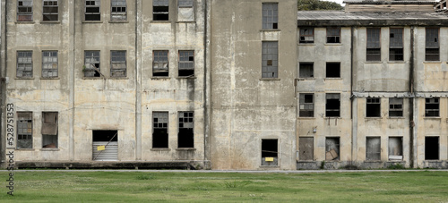 An Old abandoned building facade architecture with broken window ,concrete surface and green lawn