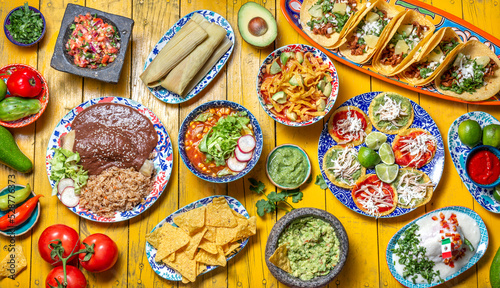 Mexican festive food for independence day independencia - chiles en nogada, tacos al pastor, chalupas pozole, tamales, chicken with mole poblano sauce. Yellow background.