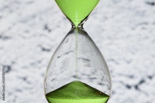Detalle de un reloj de arena de color verde, contando el tiempo, sobre diferentes fondos 
