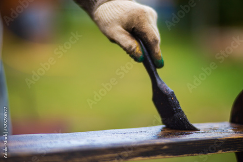 A man applies paint to a wooden surface with a brush. Lacquer work