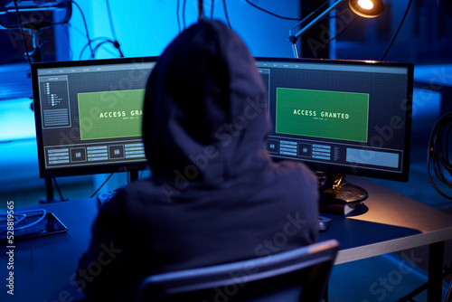 cybercrime, hacking and technology concept - hacker in dark room breaking security system or using computer virus program for cyber attack
