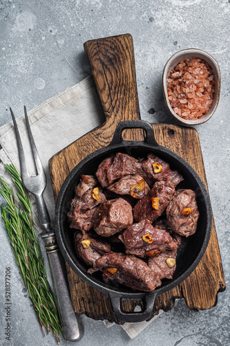 Grilled Sauteed Diced Beef in a skillet with garlic. Gray background. Top view