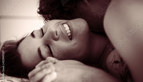Young passionate couple kissing for intense sex in the bedroom at home, young tender lover touching the skin of a sexy sensual lady moaning and making love. Foreplay concept. Retro vintage sepia tones