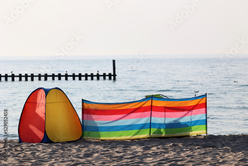 Parawan słoneczny na plaży nadmorskiej w wakacje razem z parawanem na wiatr.