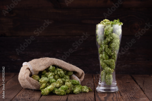 Glass of fresh green hops on wooden table