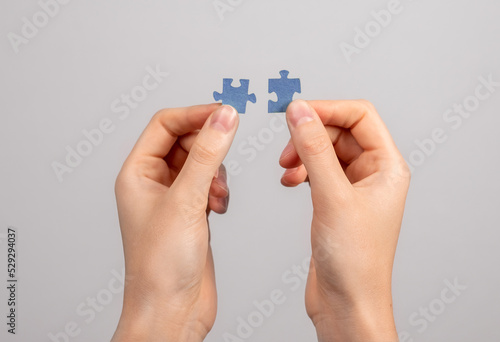 Hands connecting matching jigsaw puzzle pieces. Two details representing companies merging, joint venture, partnership, solution finding.