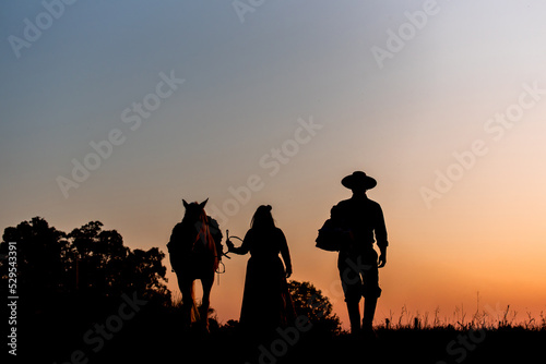 Horse and gaucho family on field at sunset silhouette