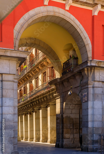 Gate to the Plaza Mayor surrounded by cafes and restaurants along the arches with a view to Calle de de Ciudad Rodrigo in Madrid, Spain