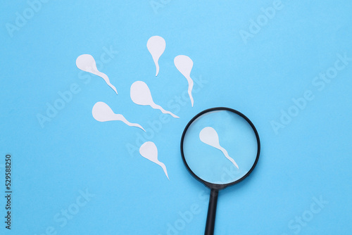 Diagnosis of male reproductive function. Spermatozoa, male seed with a magnifying glass on a blue background