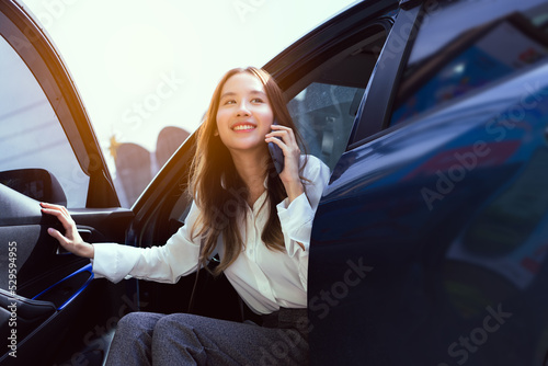 Confidence of asian business woman getting out of the car her use mobile phone calling in the modern city. people lifestyle.