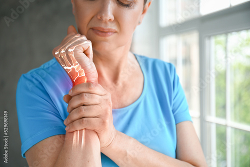 Mature woman having pain in wrist at home