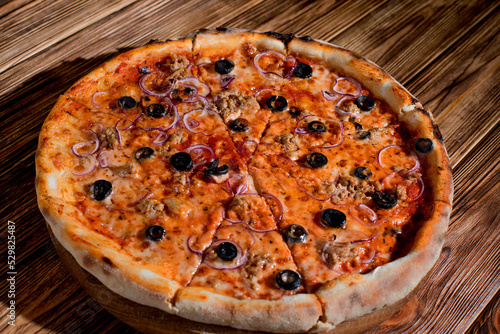 Pizza with tuna, olives, onions, mozzarella cheese and tomato sauce on wood background. Top view, copy space