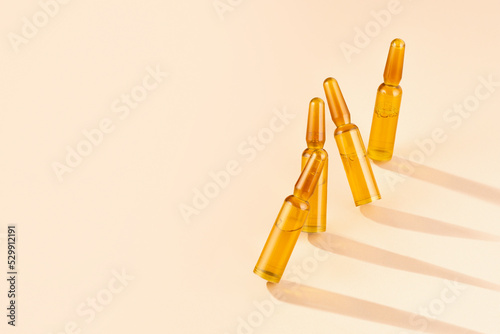 Cosmetic ampoules with serum on cream-coloured beige background with shadows and caustic. Beauty hair, Rejuvenation and cosmetics for skin care. Concept Self-care, spa and wellness. Copy space.