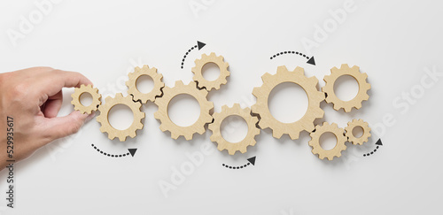 Business process and workflow automation with flowchart. Hand holding wooden cog flowing process management on white background