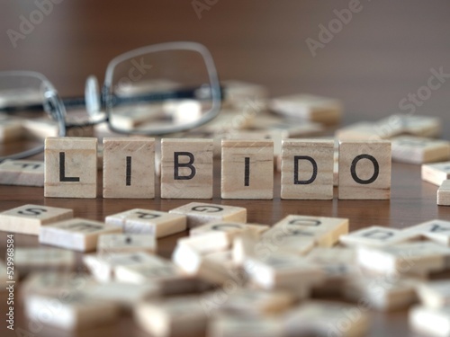 libido word or concept represented by wooden letter tiles on a wooden table with glasses and a book