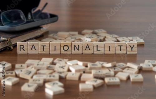 rationality word or concept represented by wooden letter tiles on a wooden table with glasses and a book