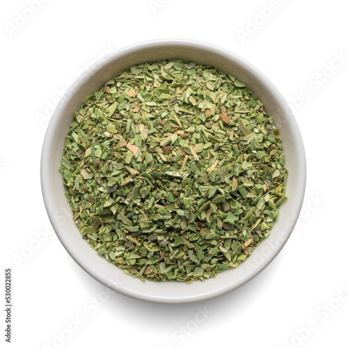 Dried oregano seasoning in round bowl isolated on white. Top view.