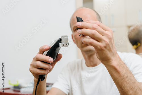 Man changing nozzle of electric hair cutting machine before shaving