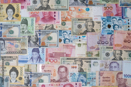 Closeup of variety banknote around the world include dollar Yuan Baht Peso Won for currency exchange or Forex investment and money payment transfer concept.