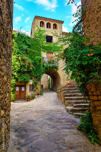 Beautiful and picturesque square with stone arches in the streets and high stairs in Madremanya, Girona, Spain.