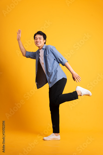 full body image of asian man posing on yellow background