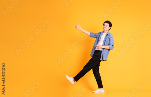full body image of asian man posing on yellow background