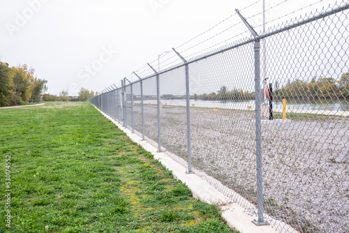 Chain-link fence along a navigable canal on a raining autumn day. Security concept.