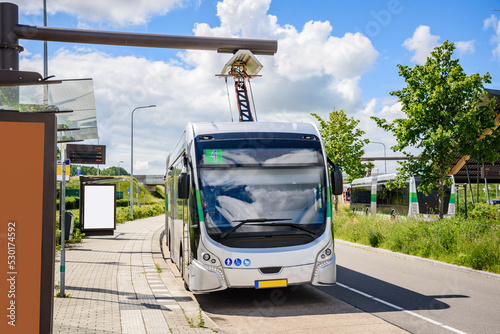 Electric bus being recharged at bus station on a sunny summer day