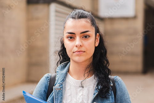 Young hispanic serious girl brunette student looking serious at camera. Juvenile teenage lady standing at university campus. Education concept. High quality photo