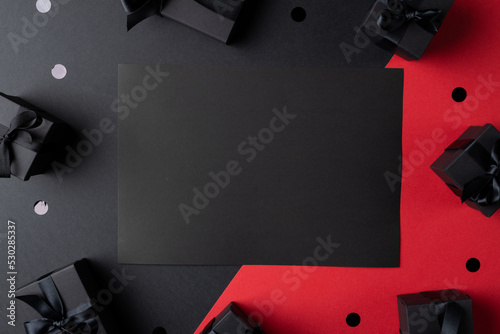 Composition of presents and black card with copy space on gray and pink background