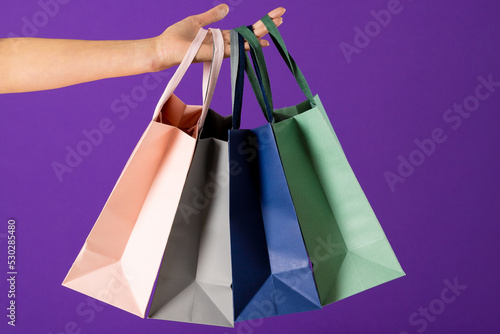 Composition of hand holding shopping bags on blue background