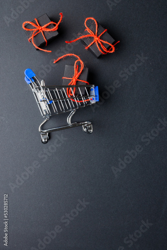 Composition of shopping cart with presents and copy space on gray background