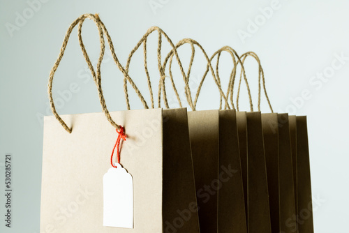 Composition of gift tag and paper shopping bags on white background