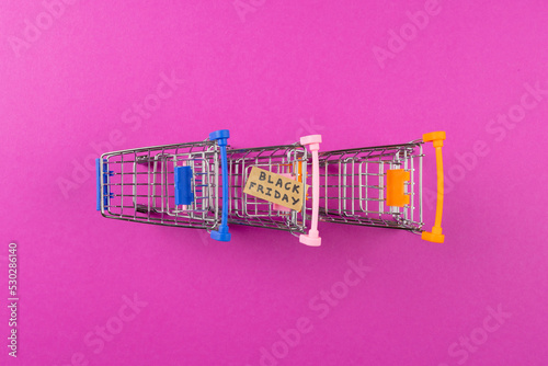 Composition of shopping carts with black friday text on pink background
