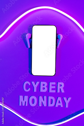 Image of cyber monday text, smartphone with copy space and earphones over neon purple background