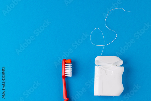 Image of toothbrush and dental string on blue surface