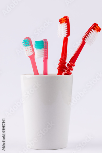 Vertical image of toothbrushes in cup on grey background