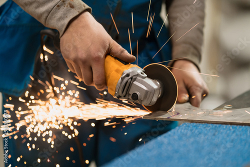 Technician worker cutting metal with many sharp sparks. Using equipments to cat iron