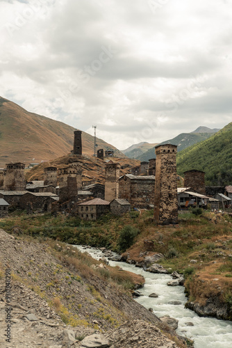 View of Ushguli village with stone high traditional towers and old houses with mountain and reaver view on background