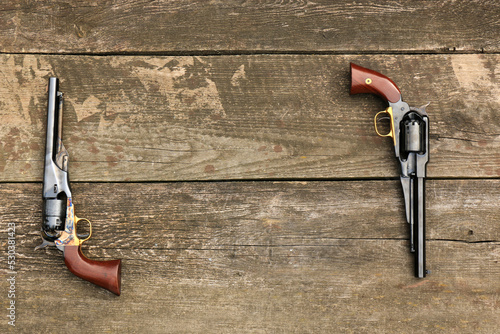 Two black powder revolvers Colt Army and Remington New Army on an old board form a frame