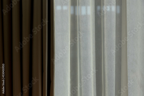 Light and shadow concept, Classic see through white sheer curtains hanging by the window in the room with sunlight and blurred outside view, Fabric and linen background.