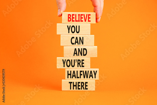 You can symbol. Concept words Believe you can and you are halfway there on wooden blocks on a beautiful orange table orange background. Businessman hand. Business motivational and you can concept.