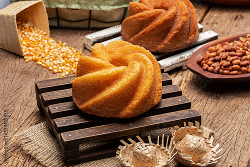 Homemade cornmeal cake made from corn on a mini dark wooden pallet on a rustic wooden table with other typical sweets from Festa Junina, a typical Brazilian festival