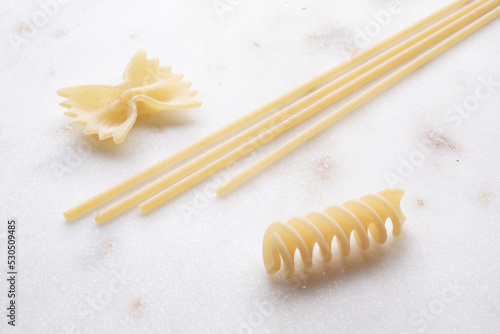 small composition of durum wheat pasta on white marble background