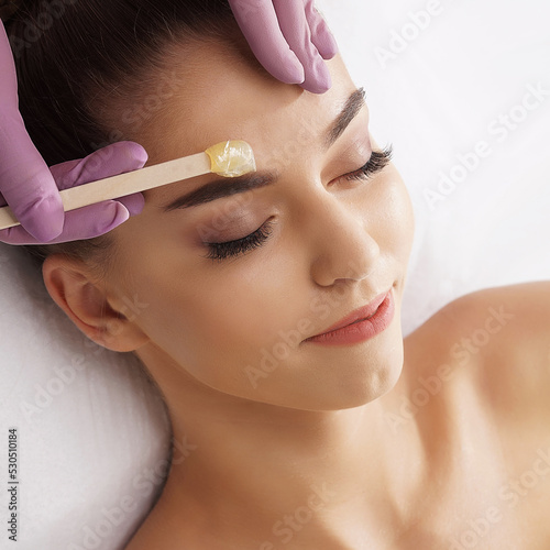 Hair removal, beauty and health concept. A young girl is getting an epilation procedure. A processional beauty worker is making depilation with hot wax.