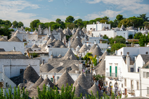  typical trulli houses in Alberobello, Puglia, Italy. Traditional symbols are painted on the conical roofs. A trullo is a traditional Apulian stone dwelling in Itria Valley. 