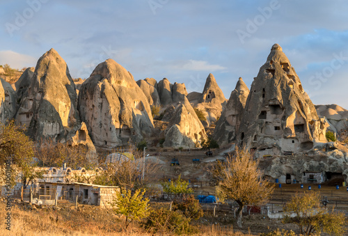 The view on partly collapsed natural rock formations and artificial caves, dovecotes inside it, known as fairy chimneys, located in Goreme, Cappadocia region, Turkey, illuminated by sun