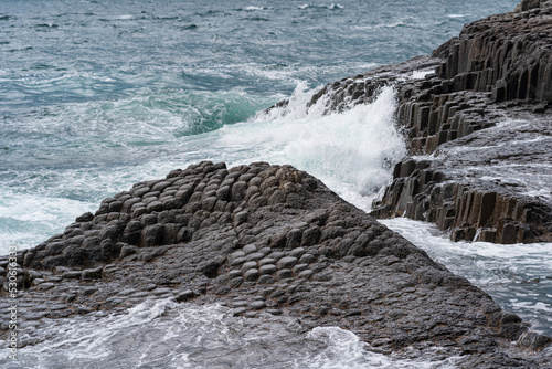 severe rocky seashore composed of columnar basalt against the stormy sea, coastal landscape of the Kuril Islands