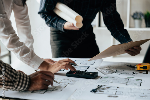 Close up of hands working brainstorming and measuring for cost estimating on paperworks and floor plan drawings about design architectural and engineering for houses and buildings.